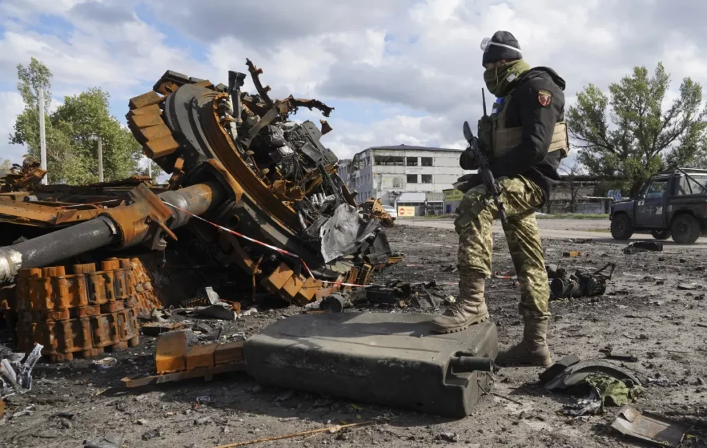 A Ukrainian soldier stands near pieces of a Russian tank Tuesday in the Kharkiv region.(Andrii Marienko / Associated Press)